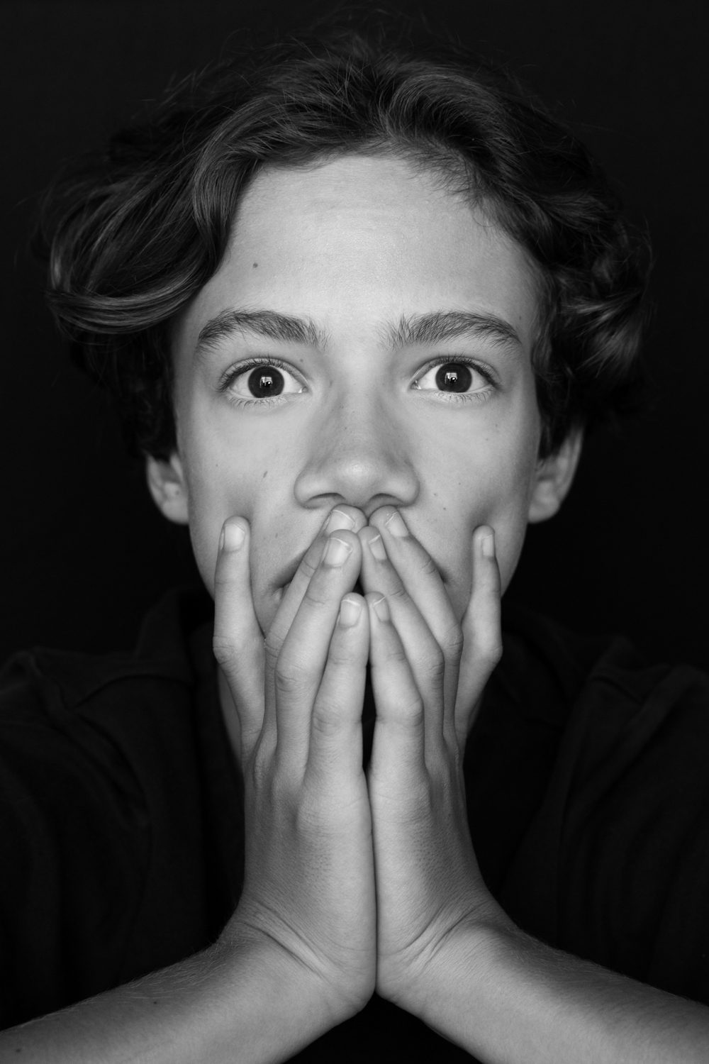 Garçon les mains devant la bouche, regard expressif