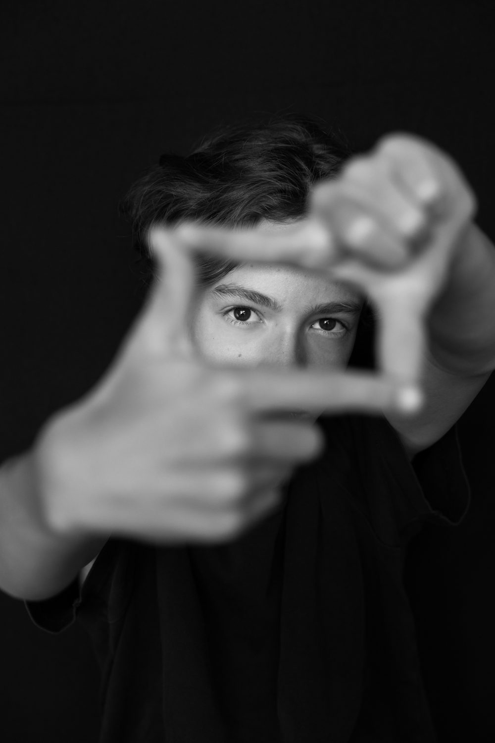 Garçon faisant un cadre avec ses doigts devant son œil