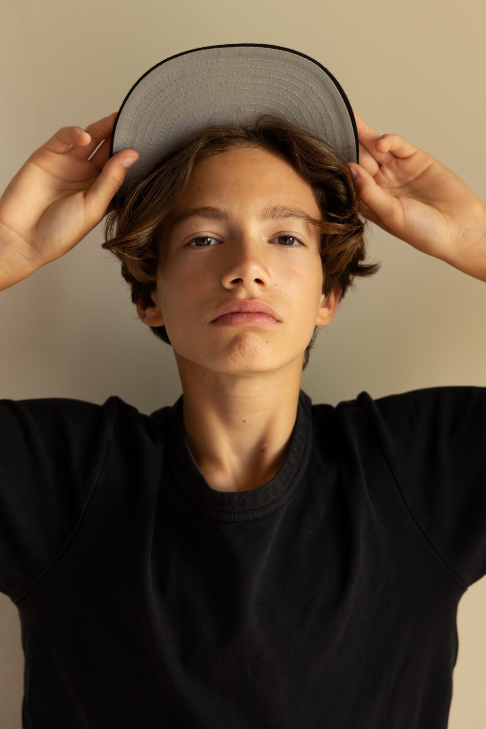 Garçon regardant la caméra, main sur la visière de sa casquette