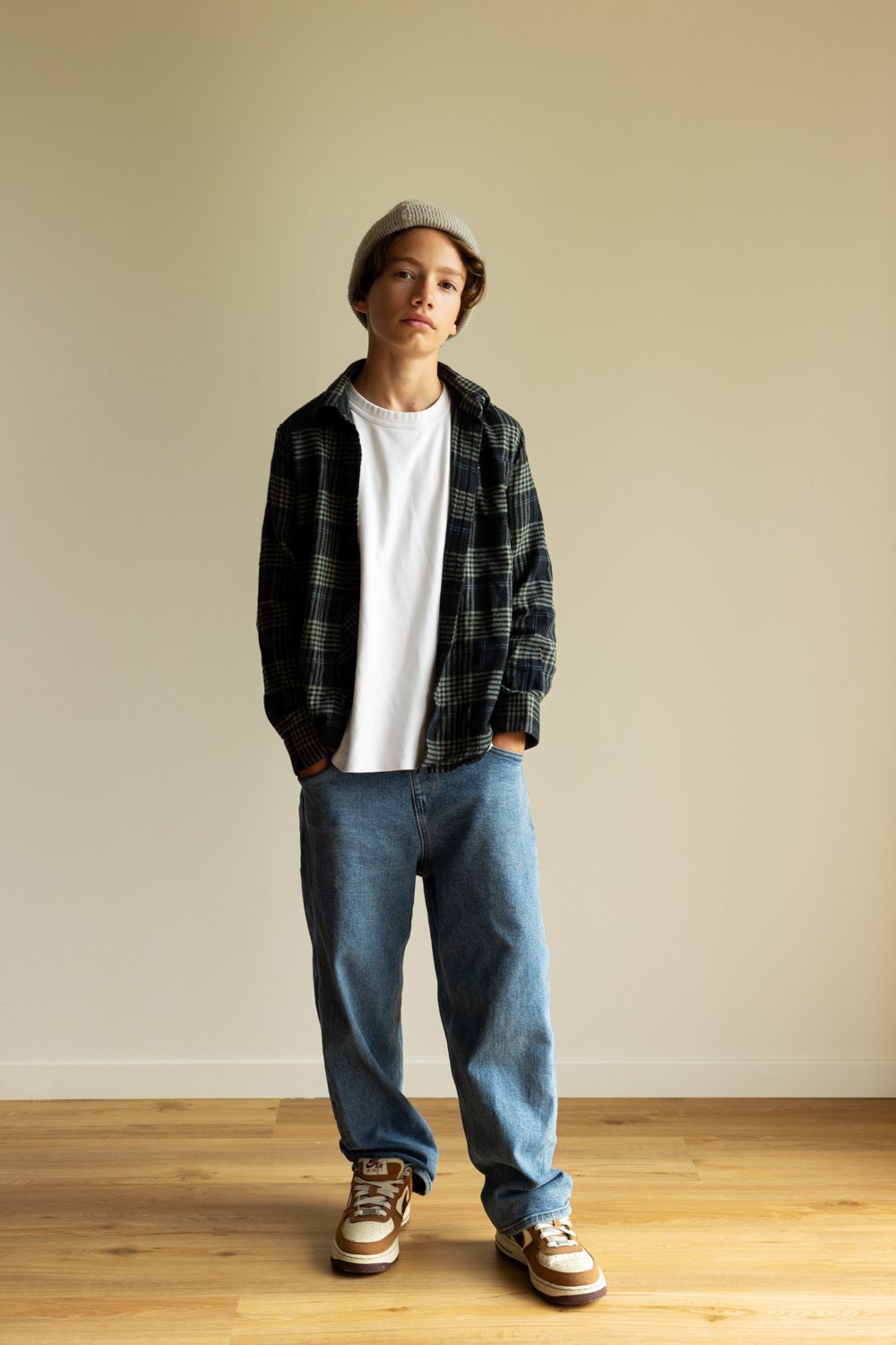 Jeune homme debout contre un mur clair, regard face caméra