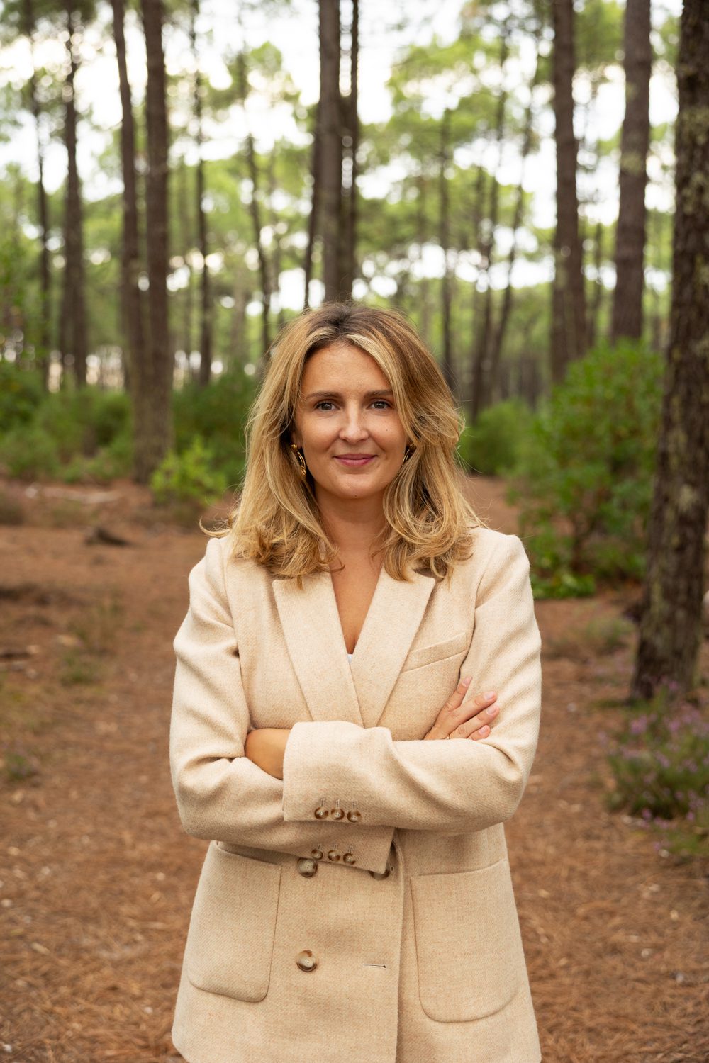 Femme souriante debout en forêt, bras croisés avec une veste de costume