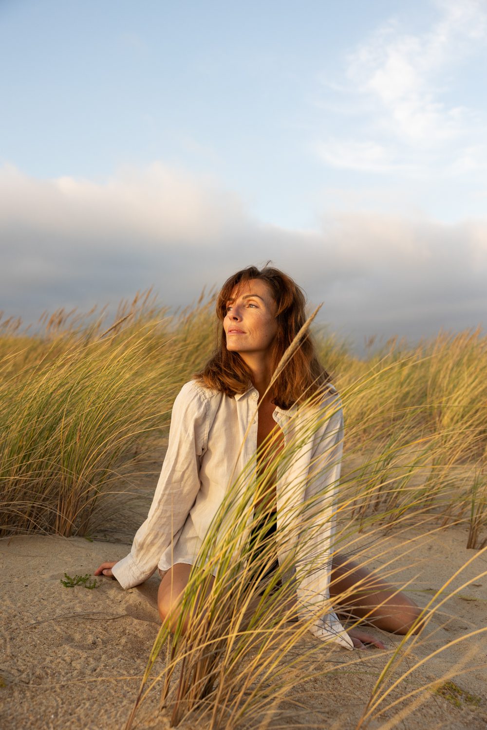 Femme assise dans les dunes, regard vers la droite