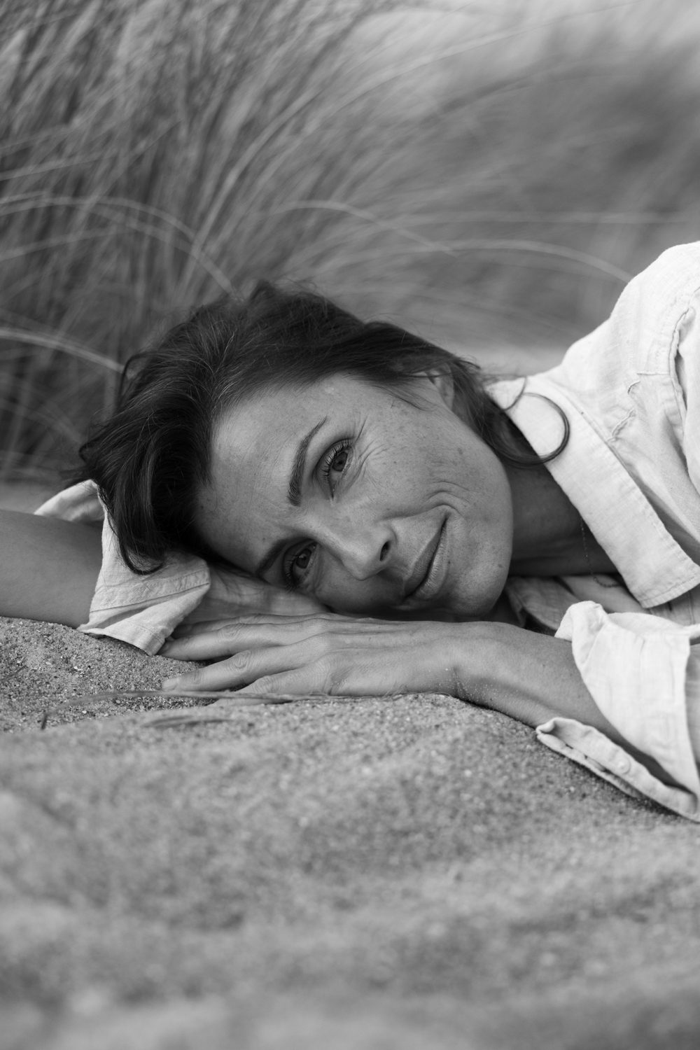 Femme allongée dans le sable, regard doux, en noir et blanc