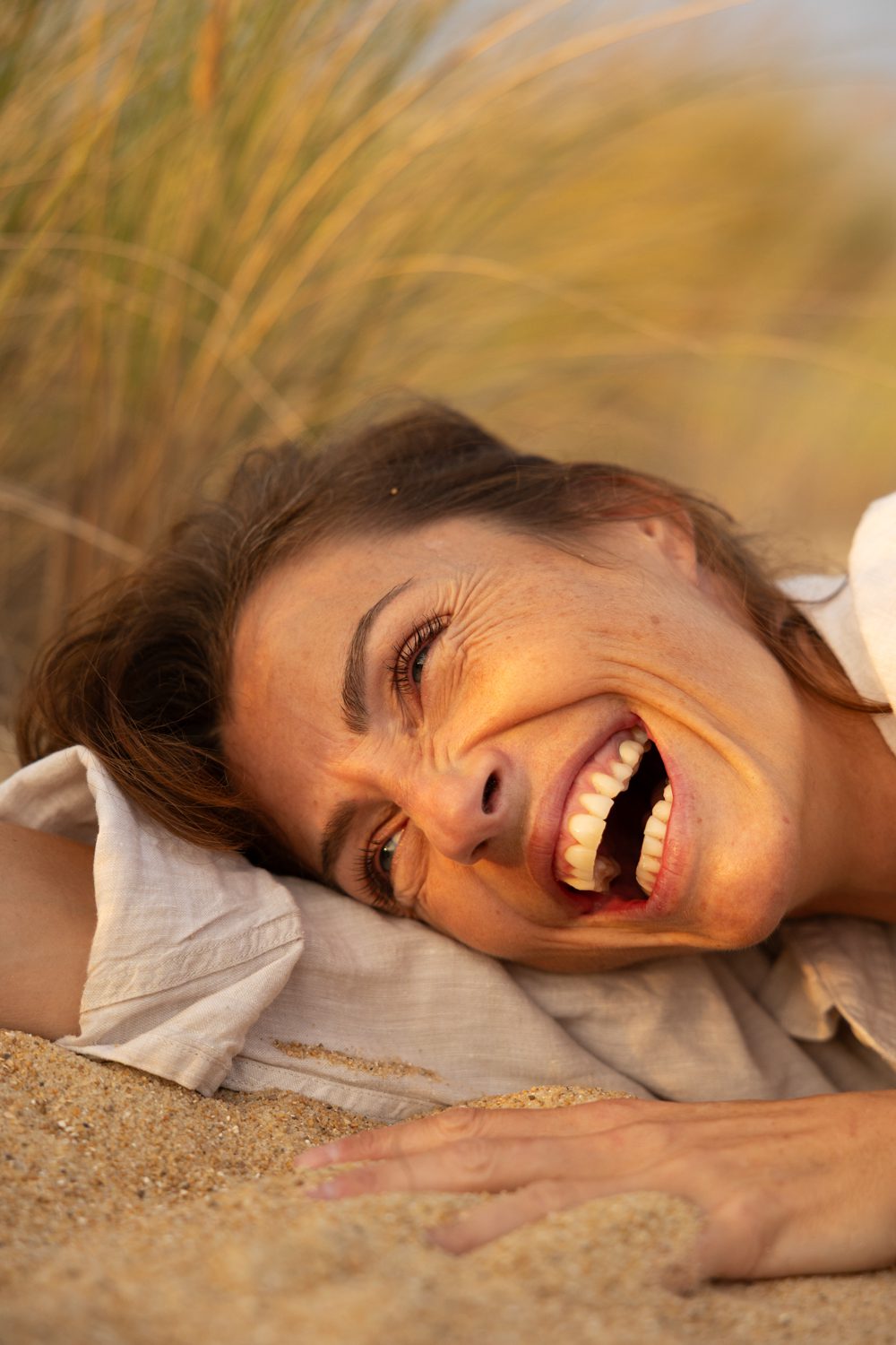 Femme allongée dans l’herbe, souriante, lumière dorée