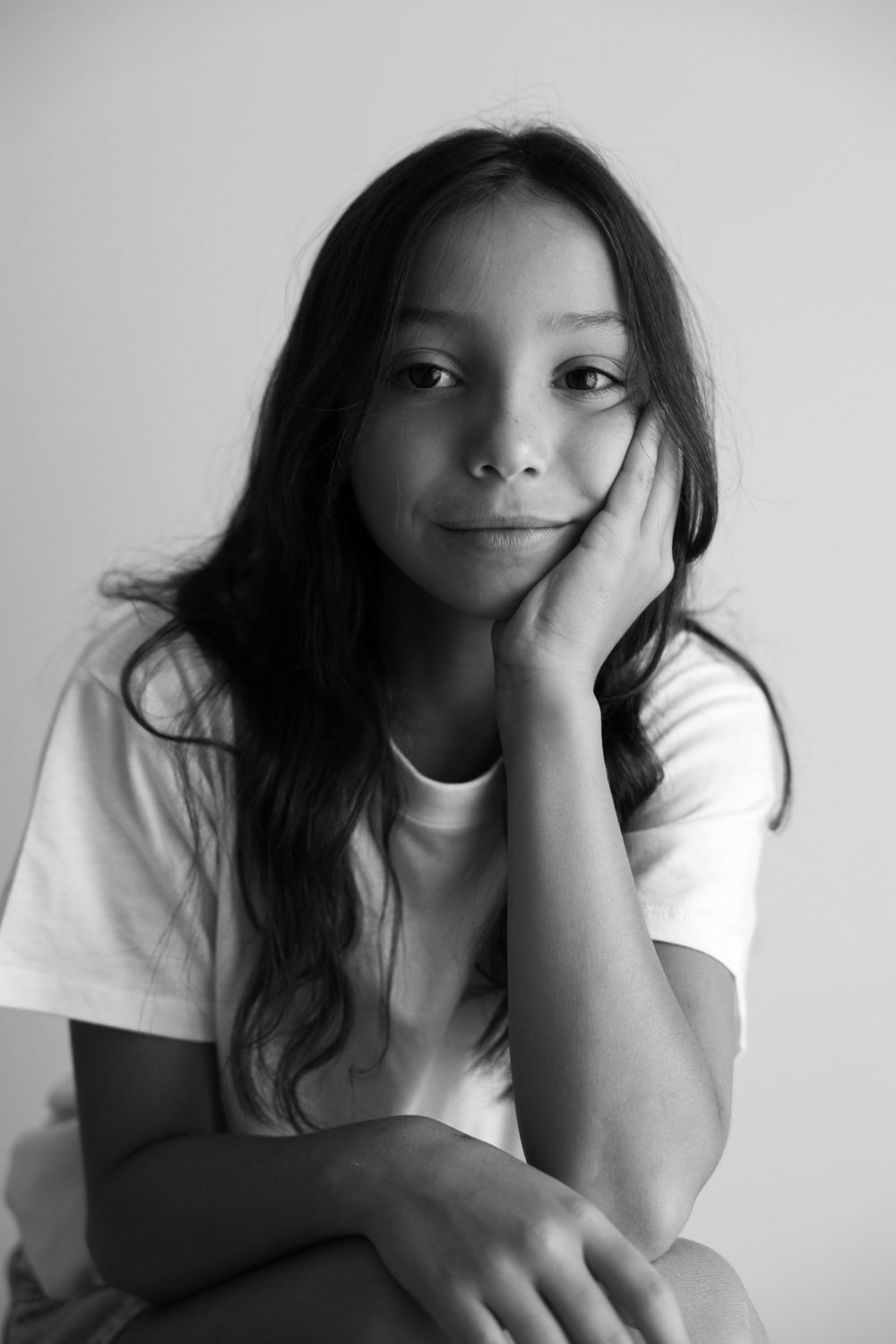 Fille posant la tête sur ses mains, regard face caméra