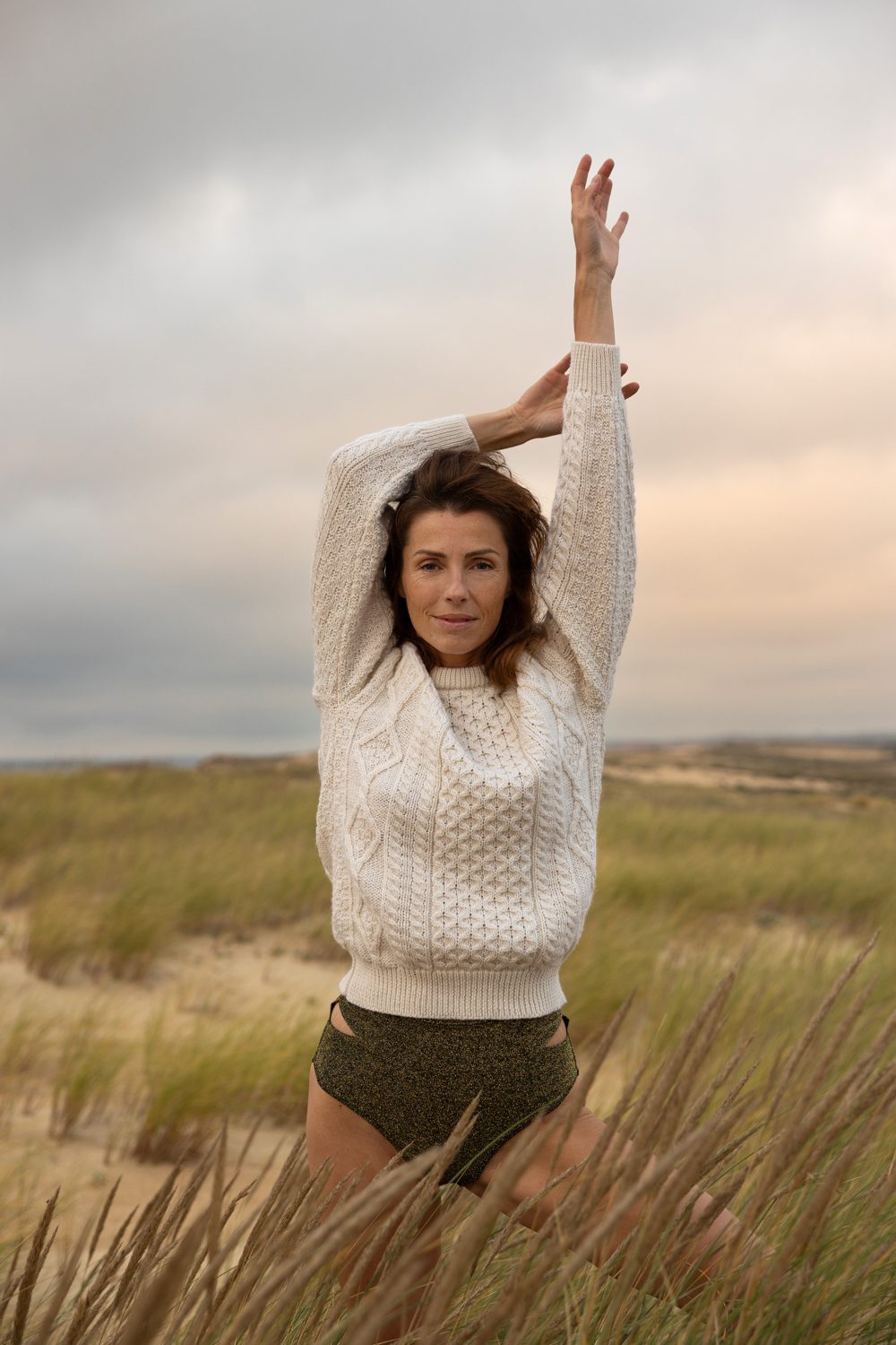 Femme debout dans les dunes, bras levé