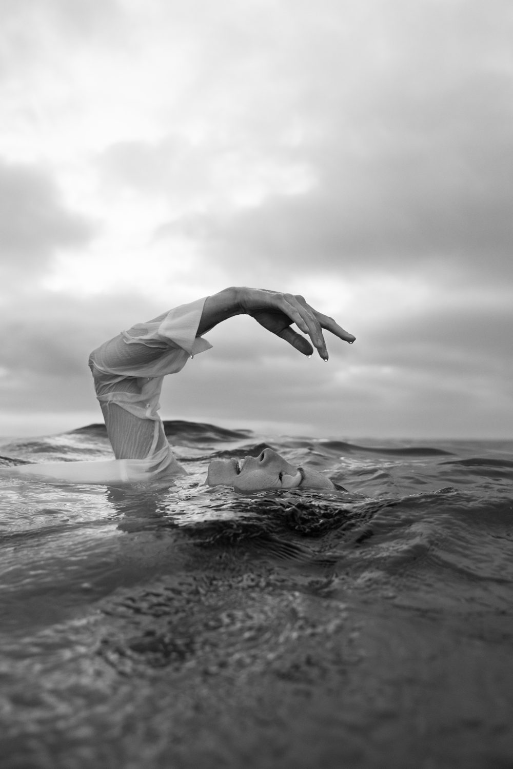 Femme flottant sur l’eau, bras hors de l’eau, en noir et blanc