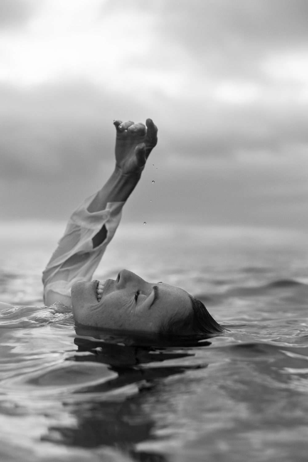 Femme flottant sur l’eau, bras hors de l’eau, en noir et blanc