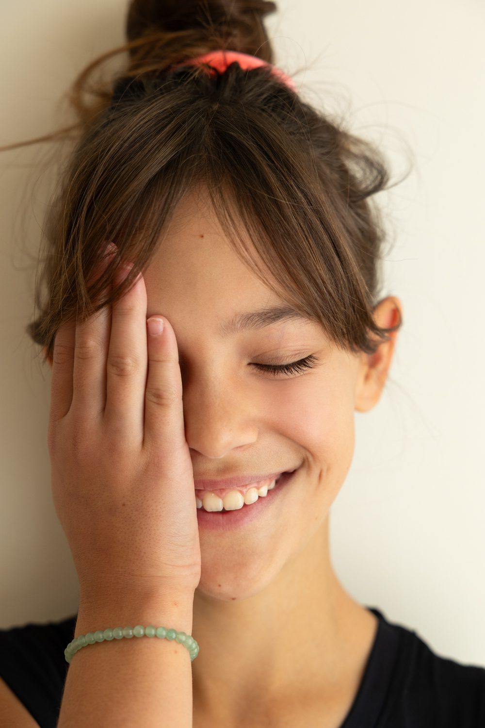 Fille riant, main devant le visage