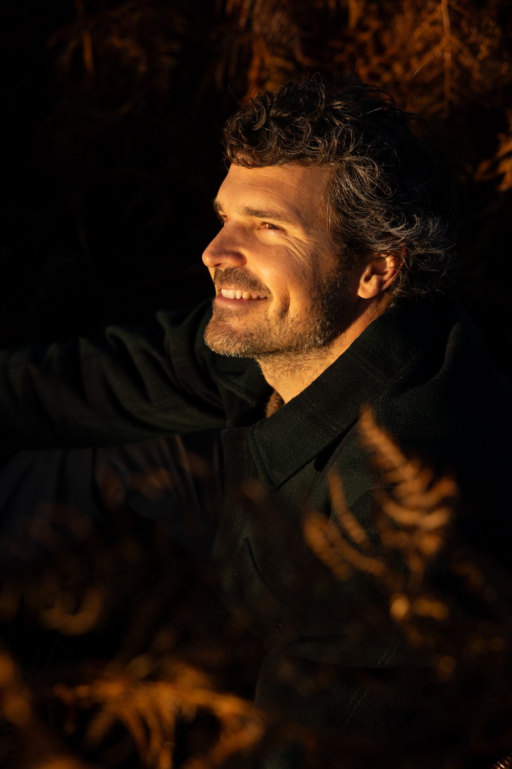 Homme souriant, portrait serré, fond sombre