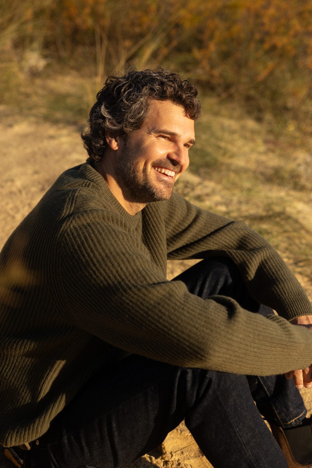 Homme assis dans l’herbe, souriant